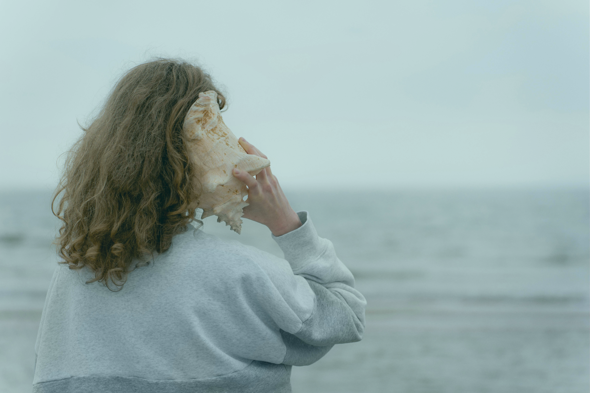 Woman holding a conch to represent the joyful of hearing the natural sound again, conveying the benefit of wearing a hearing aids