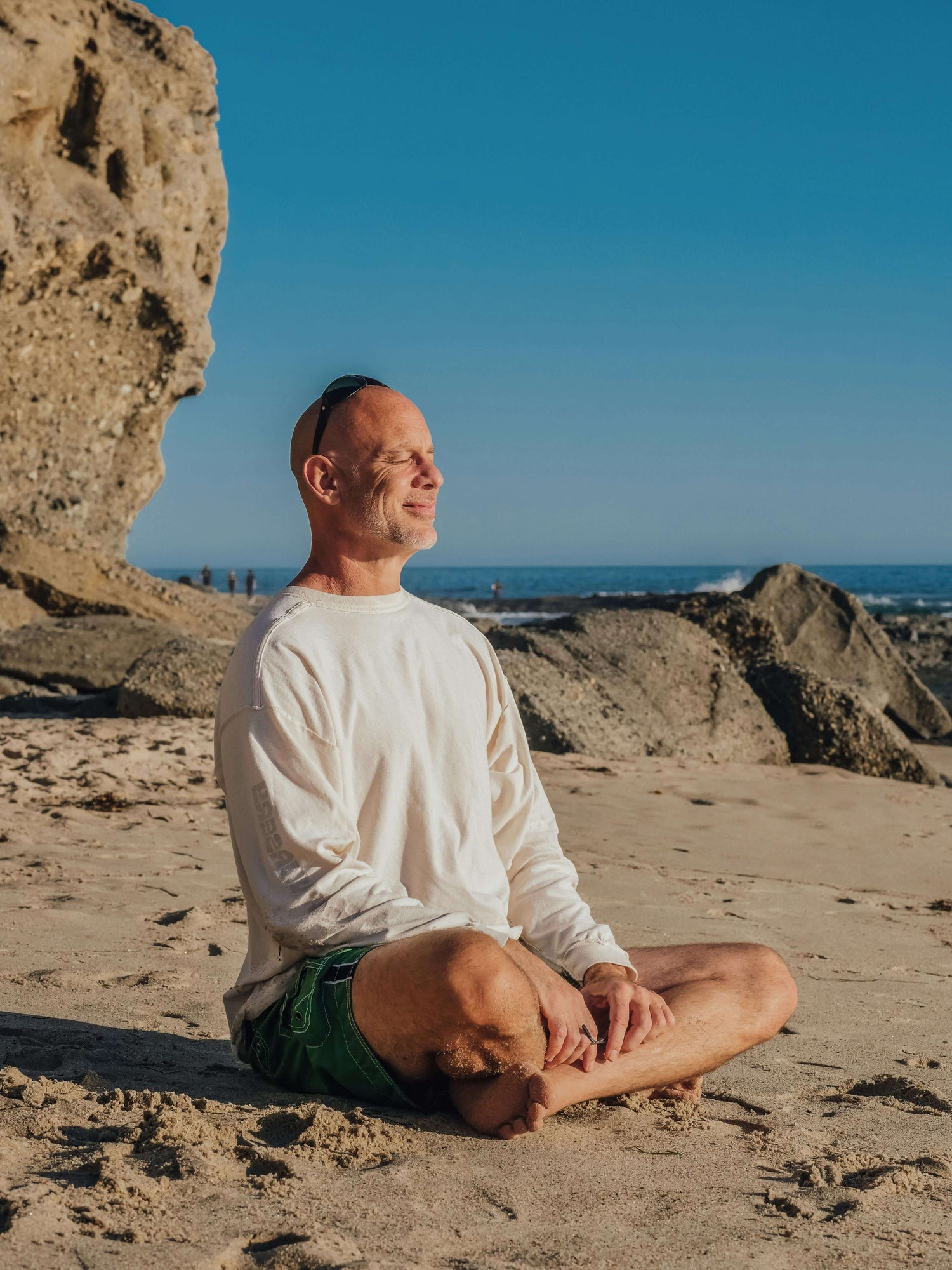 Middle-aged man relaxing on the beach, enjoying clear sound and peace with affordable OTC hearing aids.
